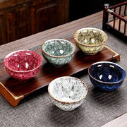 Five porcelain tea cups displayed on a tea tray