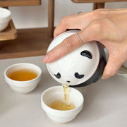 Panda travel teapot pouring tea into a small cup