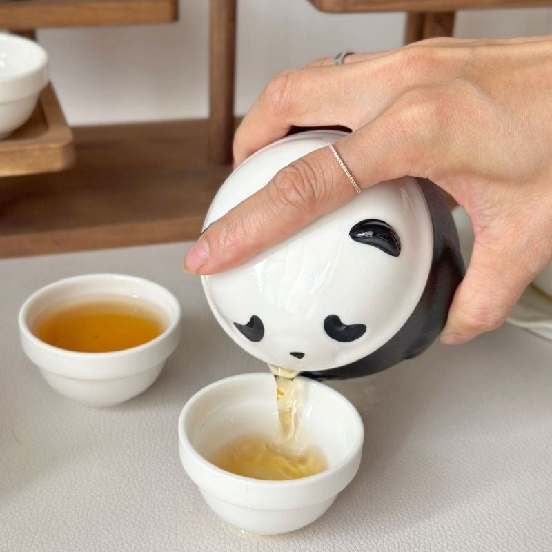 Panda travel teapot pouring tea into a small cup