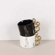 Black and white Piano Key Tea Cup closeup showing ceramic body and gold treble clef handles