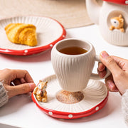 Red mushroom ceramic cup and saucer with tea and round dessert plate in background