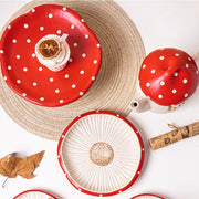 Red mushroom ceramic dessert stand round plate and teapot flat lay